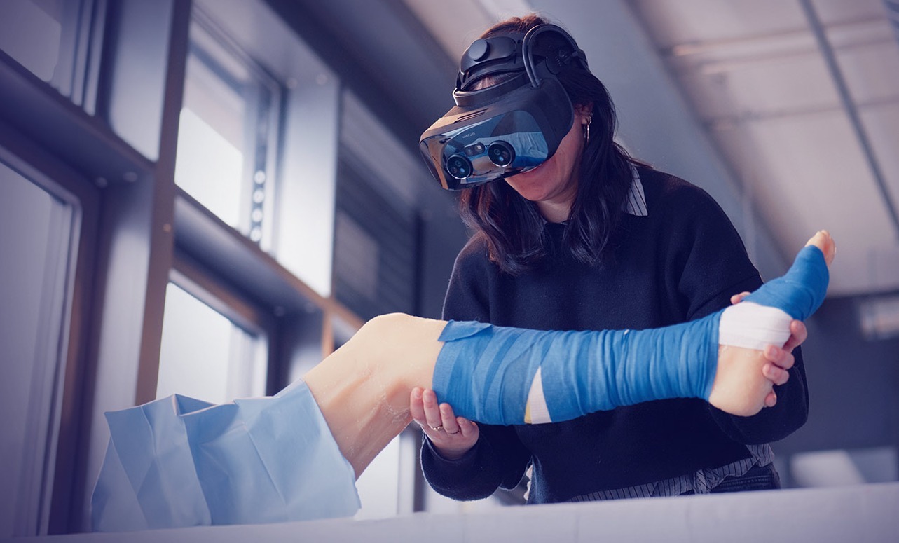 A woman wears VR goggles and lifts a silicone leg
