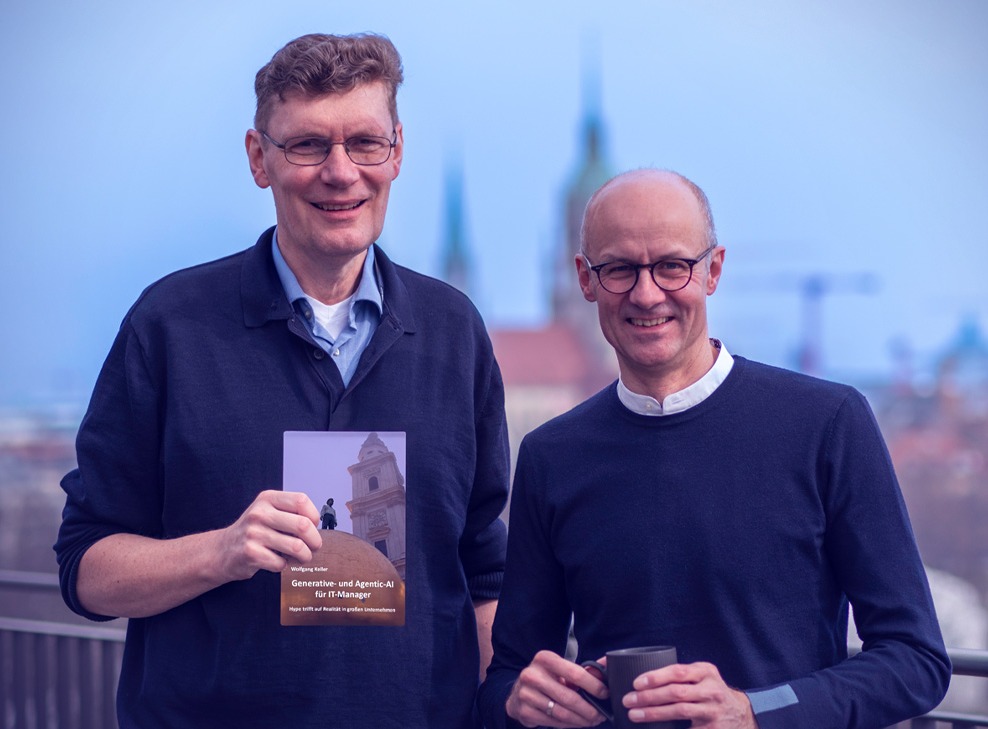 Two men are standing on a rooftop terrace, smiling