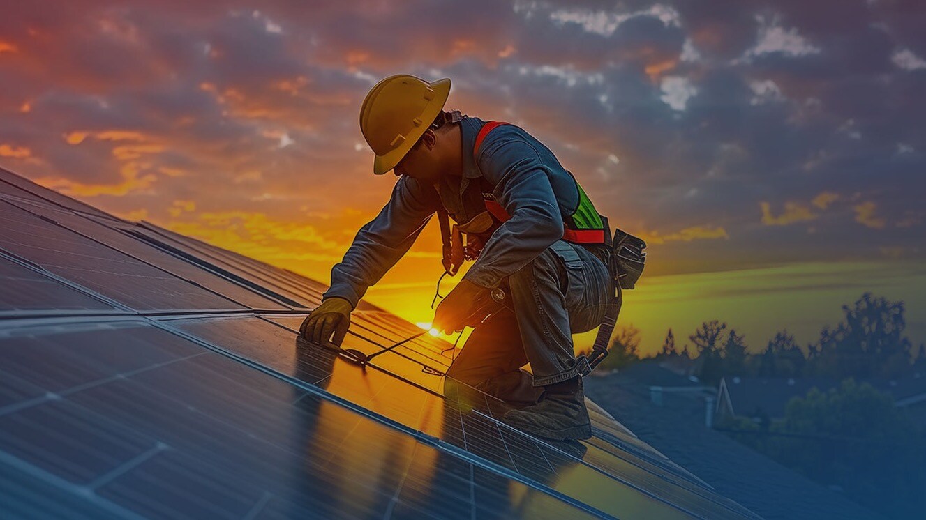 Technician installs solar panel on roof at sunset