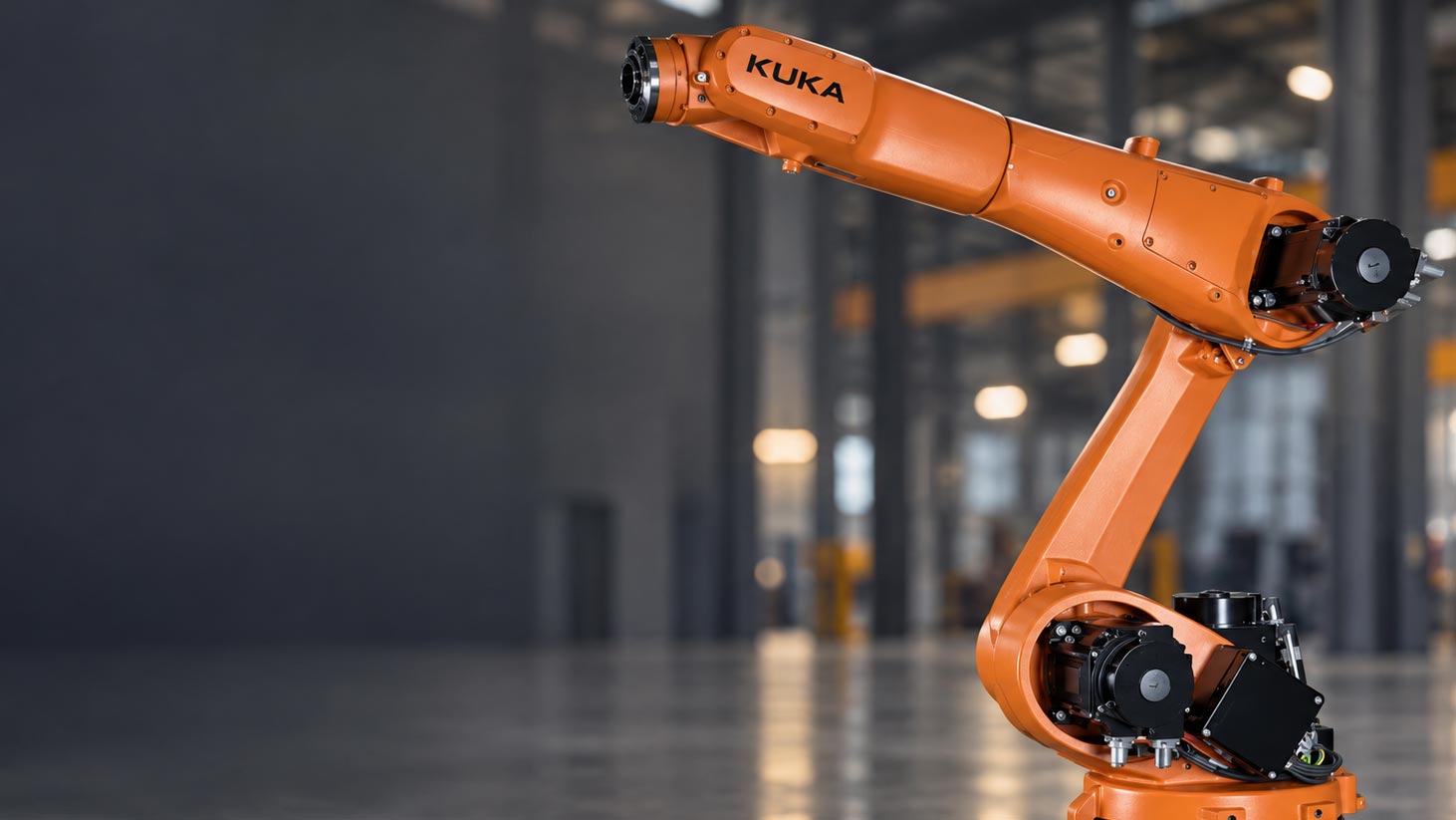 Orangefarbener Industrieroboterarm von KUKA in einer Fertigungshalle