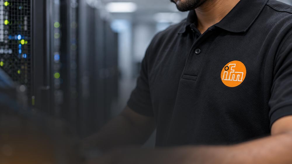 Person in schwarzem Poloshirt mit ifm-Logo vor Serverschränken in einem Rechenzentrum