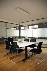 Meeting room with wooden floor and a table with several chairs and glazed walls.