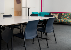 A meeting room with a table, chairs and a sofa against the wall.