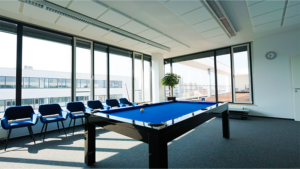 Our recreation room with large pool table with blue cover and blue armchairs.