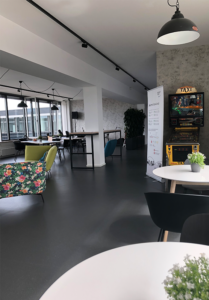 View into our bistro area with tables, chairs, armchairs and a pinball machine.