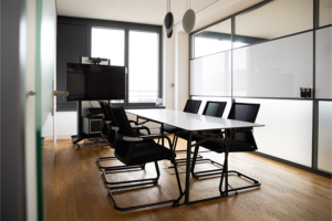 Small meeting room with long table, 6 chairs and a surface hub.