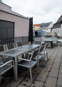 Roof terrace with chairs and tables. The focus is towards the view