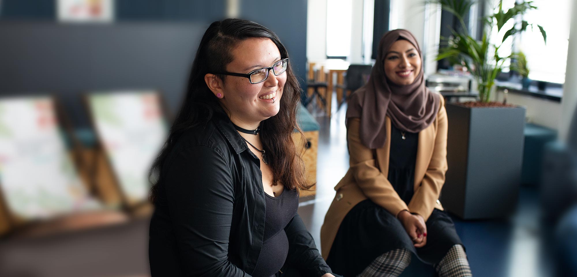 Zwei lachende junge Frauen im Büro