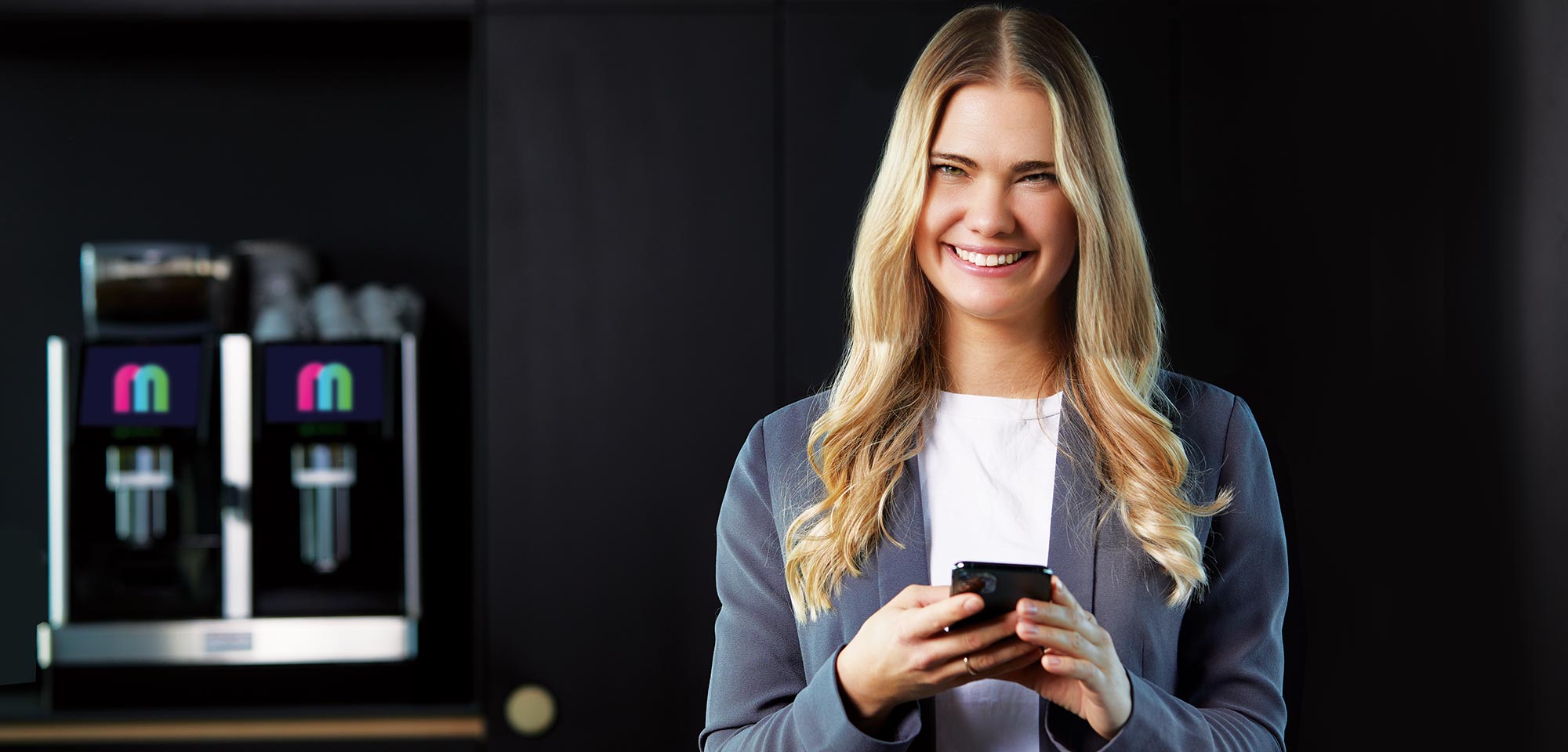 Lächelnde junge Frau mit Handy in der Hand