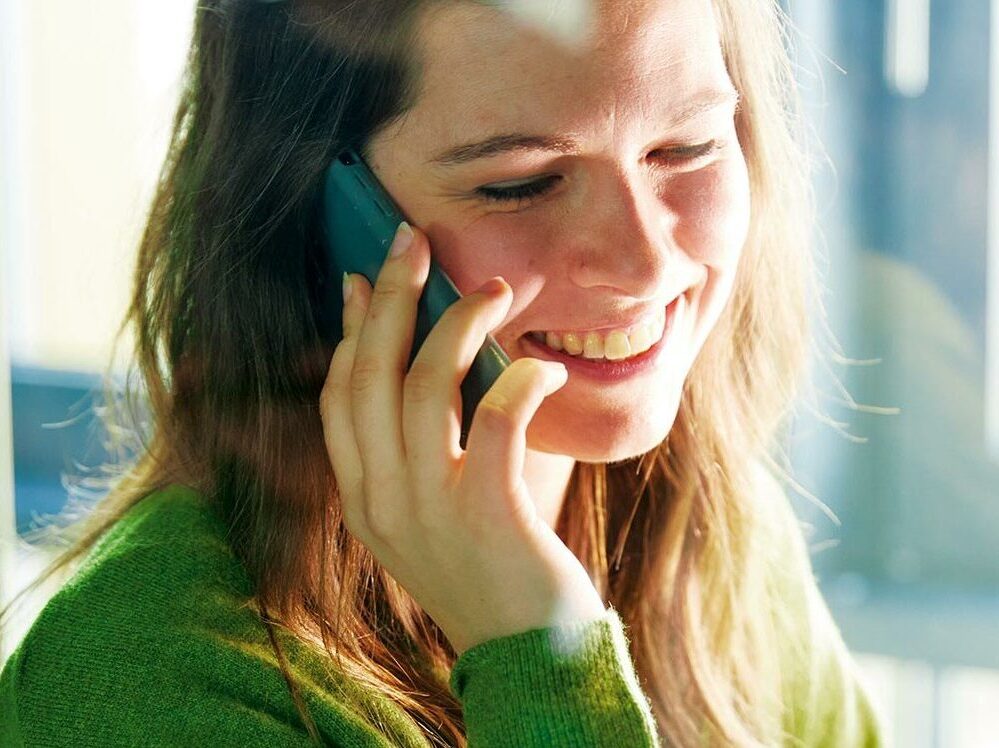 Colleague smiling carries on a conversation on the cell phone.