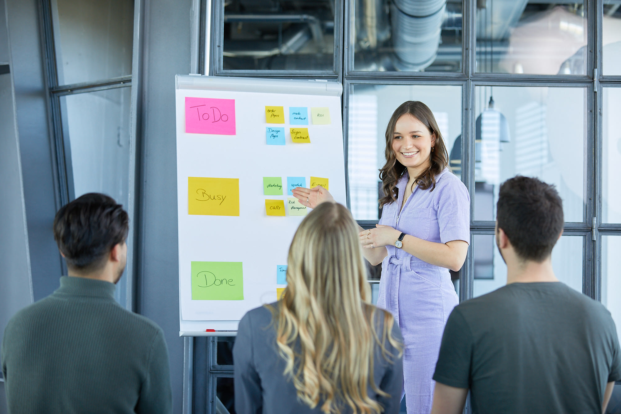 Gruppe von Mitarbeitenden vor Whiteboard mit bunten Karten