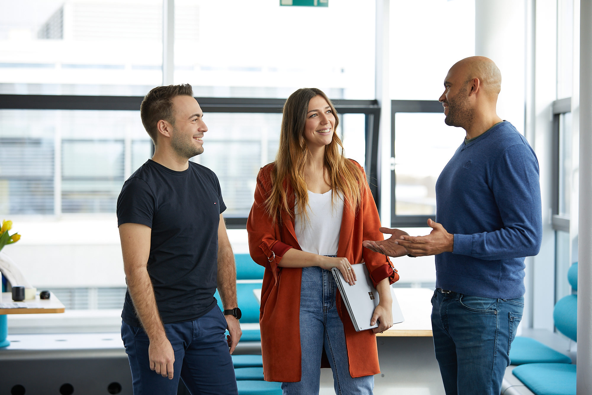 3 Mitarbeitende stehen im Büro und unterhalten sich