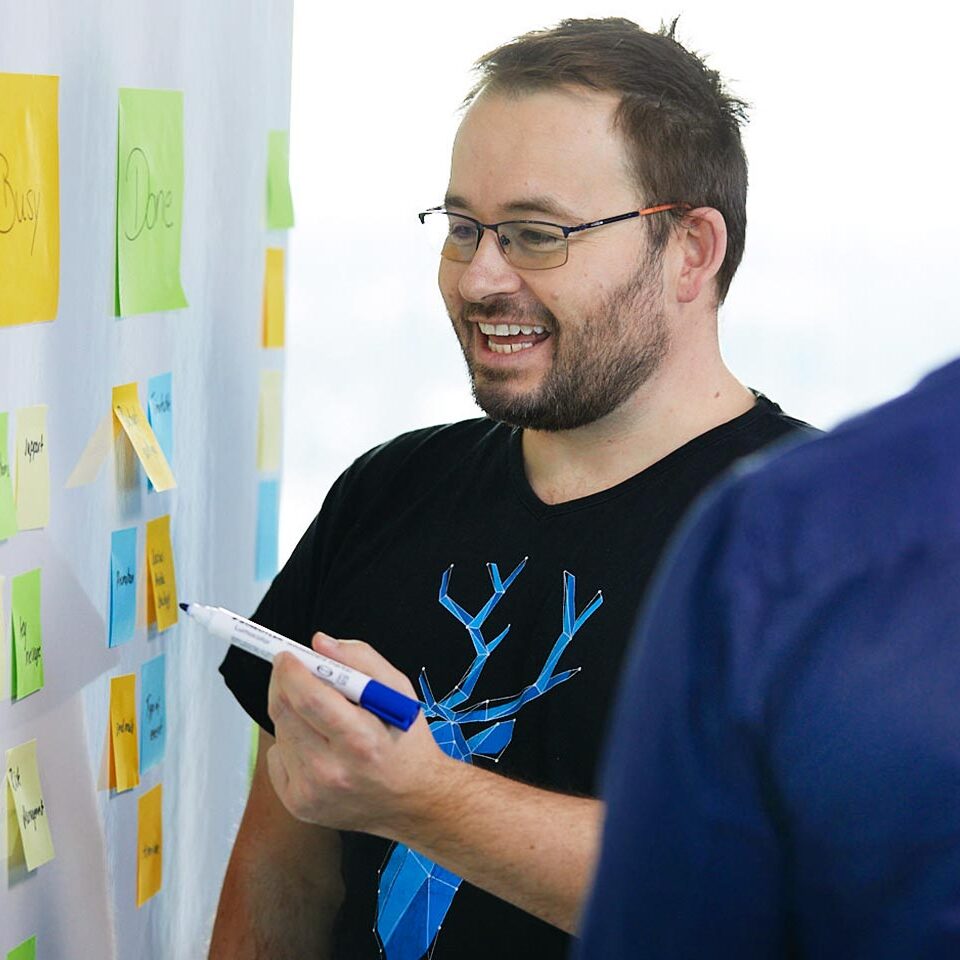 Mitarbeiter schreibt auf Whiteboard mit bunten Haftnotizen