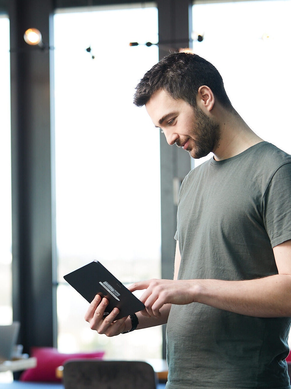 junger Mann interagiert stehend mit einem Tablet