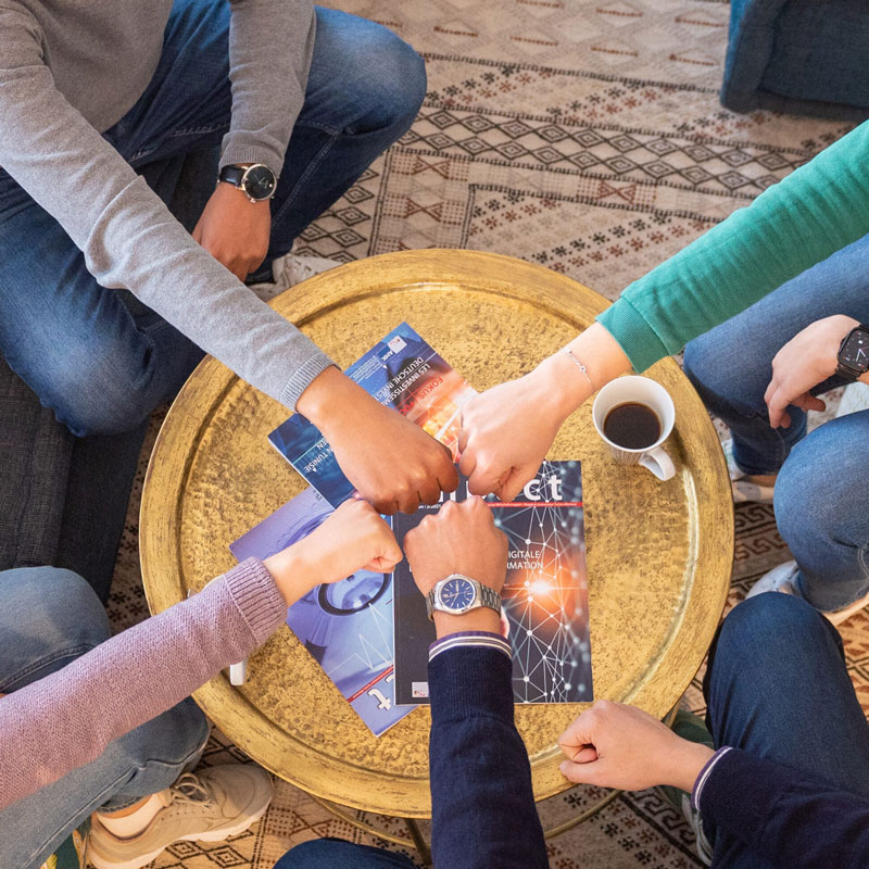 Menschen sizten an einem Tisch und stossen Fäuste zusammen