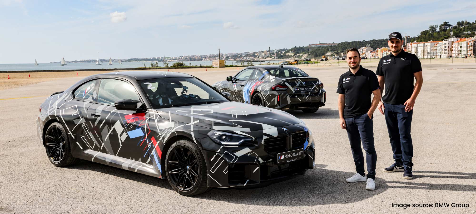 Two men standing next to a BMW car